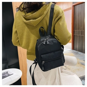 Rear view of a black nylon mini backpack with adjustable straps on a model back