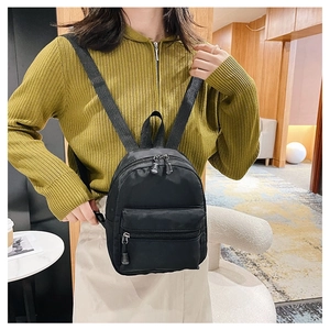 Detailed back view of a black nylon mini backpack with adjustable straps worn by a model