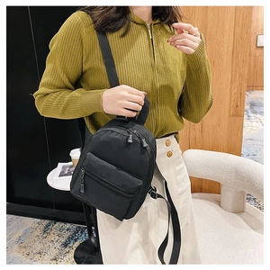 Classic black nylon mini backpack for women shown held by a model in a modern interior
