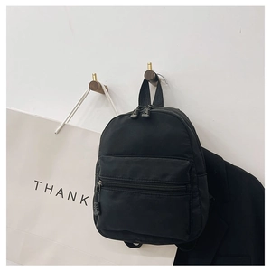 Close-up of black nylon mini backpack hanging on wooden wall hook in stylish room