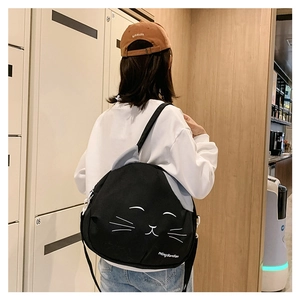 Rear view of a black cat-shaped canvas shoulder bag worn by a model in casual wear