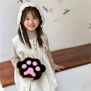 Detail of child wearing a fluffy black and pink cat paw plush bag with gold chain