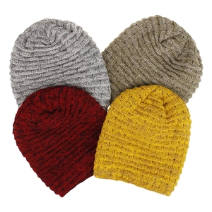 Gros plan de quatre bonnets en tricot torsadé montrant la texture et les couleurs