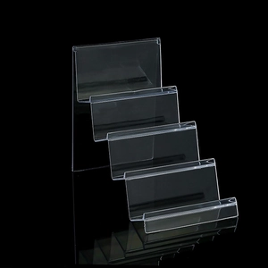 Clear acrylic four-tier display stand showing stepped structure for wallets and cosmetics