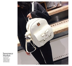 White PU leather backpack featuring bow decor and teddy bear charm on model back