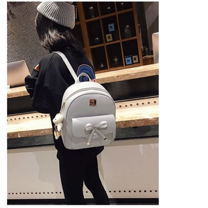 Detail of light gray PU leather backpack with bow decoration and cute bear pendant