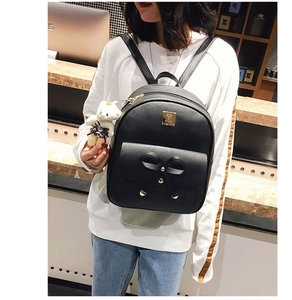 Detail view of stylish black bow backpack with crossgrain texture and bear charm