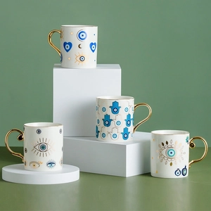 Detail of four ceramic mugs featuring gold handles and blue evil eye patterns
