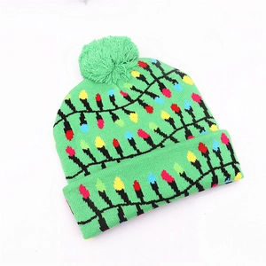 Detail of green knitted Christmas hat with colorful bulb patterns and soft top pompom