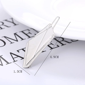 Detail view of a silver geometric hair clip on a white plate with size dimensions