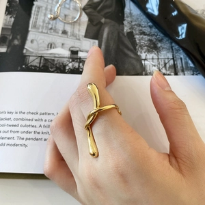 Close-up of golden liquid twist ring worn by model over a minimalist magazine backdrop