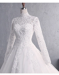 Close-up of intricate lace embroidery and sequins on long sleeve wedding dress