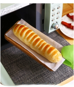 Green silicone heat resistant glove removing wooden food tray from a modern microwave