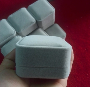 Close-up of small square grey velvet jewelry box for rings and earrings in hand
