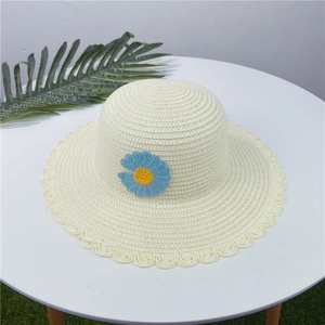 Chapeau de soleil beige en paille tissée avec fleur crochetée bleue et bord ondulé
