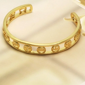 Chic gold open bangle featuring a unique cut-out smiley face pattern on textured metal