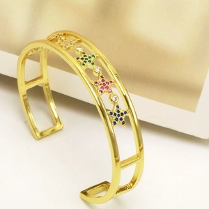 Detail of adjustable gold bangle with star charms inlaid with multicolored zircons