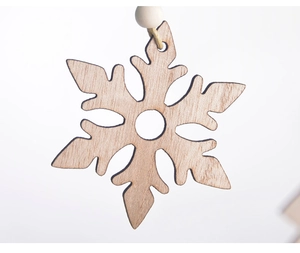 Detailed close-up of a laser-cut wooden snowflake ornament with natural grain and jute rope