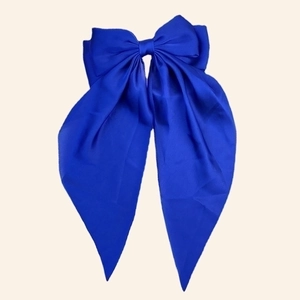 Detail of royal blue satin bow hair clip with elegant long ribbon streamers