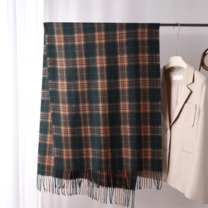 Green and orange plaid cashmere scarf with soft tassels hanging on a hanger