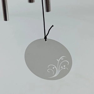 Detail of silver stainless steel wind chime featuring a hollow tree of life pattern