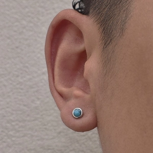 Close-up of a silver round turquoise stud earring on ear showing fit and texture