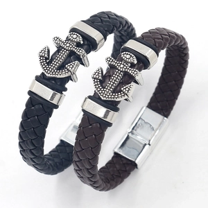 Detail of woven leather bracelets in black and brown with metal anchor charms and magnetic clasp