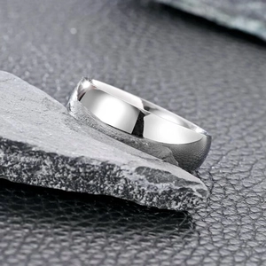 Macro shot of minimalist silver stainless steel ring on dark rock and leather