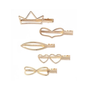 Detail of 5-piece gold metal hair clips in leaf, heart and crown shapes with crystals