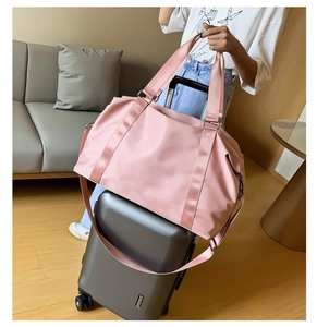 Pink waterproof travel duffel bag with luggage sleeve secured on a rolling suitcase