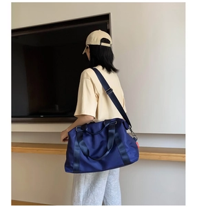 Detail of dark blue waterproof nylon travel bag with shoulder strap and side red label