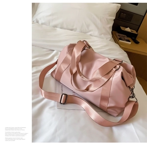 Detail of light pink waterproof fitness bag with adjustable shoulder straps on white bed