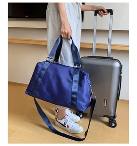 Detail of blue travel bag showing reinforced handles and detachable shoulder strap
