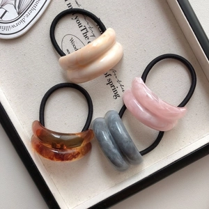 Detailed close-up of marble pattern acrylic hair ties in cream, pink, grey and amber colors