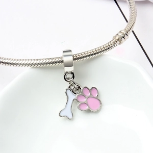 Close-up of silver dog paw and bone pendant charms on a snake chain bracelet