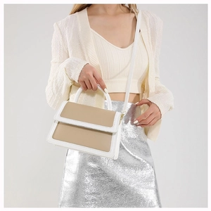 Chic two-tone flap crossbody bag in white and khaki leather worn by a model