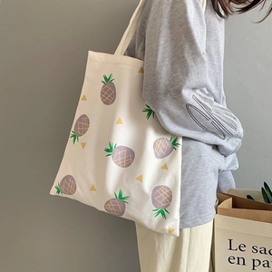 Detail of canvas tote bag with purple pineapple pattern worn on shoulder