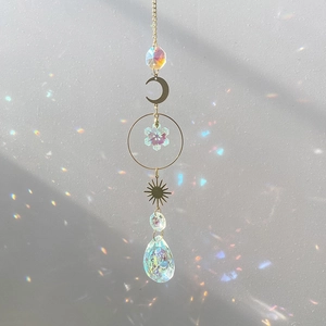 Detail of sun and moon crystal suncatcher reflecting colorful light on a white wall