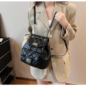Detail of black quilted leather backpack with gold chain strap and metal turn-lock