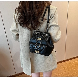 Detail of black quilted leather backpack with gold chain straps and twist lock