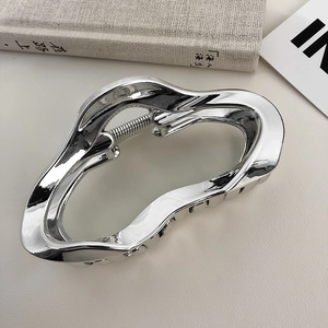 Detail of silver wavy metal hair claw clip on neutral background with soft lighting