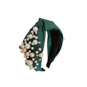 Dark green satin knotted headband featuring decorative white and champagne pearls