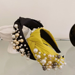 Detail of fabric knotted headbands with scattered pearls in black and bright yellow colors