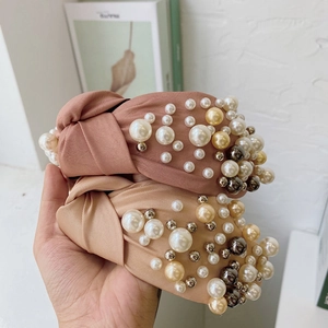 Detail of pink and beige fabric knot headbands with multicolored faux pearl embellishments