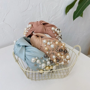 Detail of knot fabric headbands in pink and blue with white pearls in a metal basket