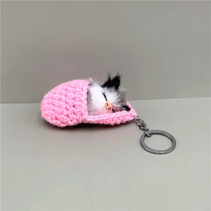 Detailed view of handmade pink crochet sleeping bag with a realistic plush cat keychain