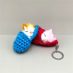 Detail of knitted sleeping cat keychains in blue and red with soft faux fur texture