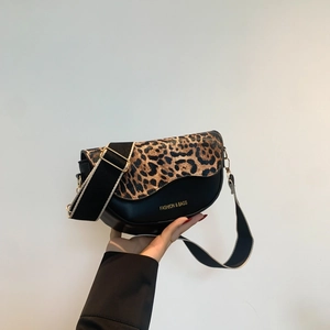 Detail of a black saddle bag with leopard print lid and adjustable wide shoulder strap