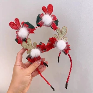 Detail of Christmas headband with glitter antlers, checkered bows, and plush pom-poms