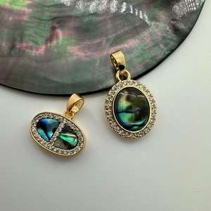Golden shell abalone pendants with zircon inlay shown on natural shell background